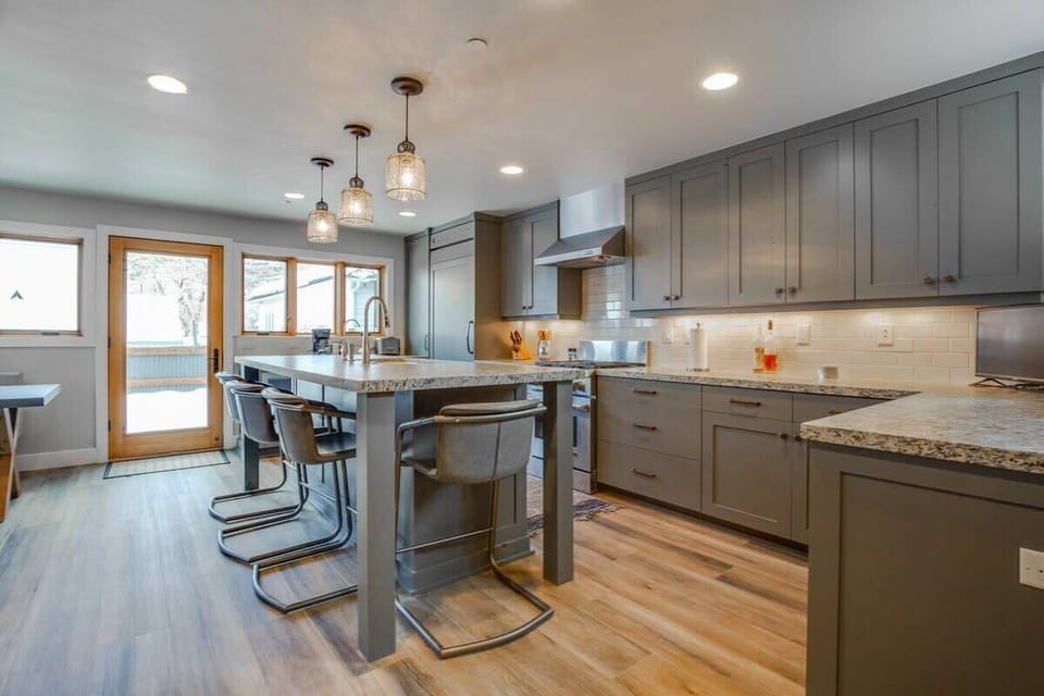 The fully equipped kitchen boasts stainless steel appliances, spacious countertops, and a large kitchen island with four bar stools.