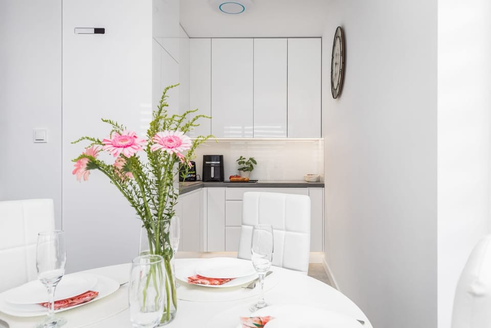 A dining area with a white table and chairs, complemented by a vase of fresh flowers for a cheerful touch.

