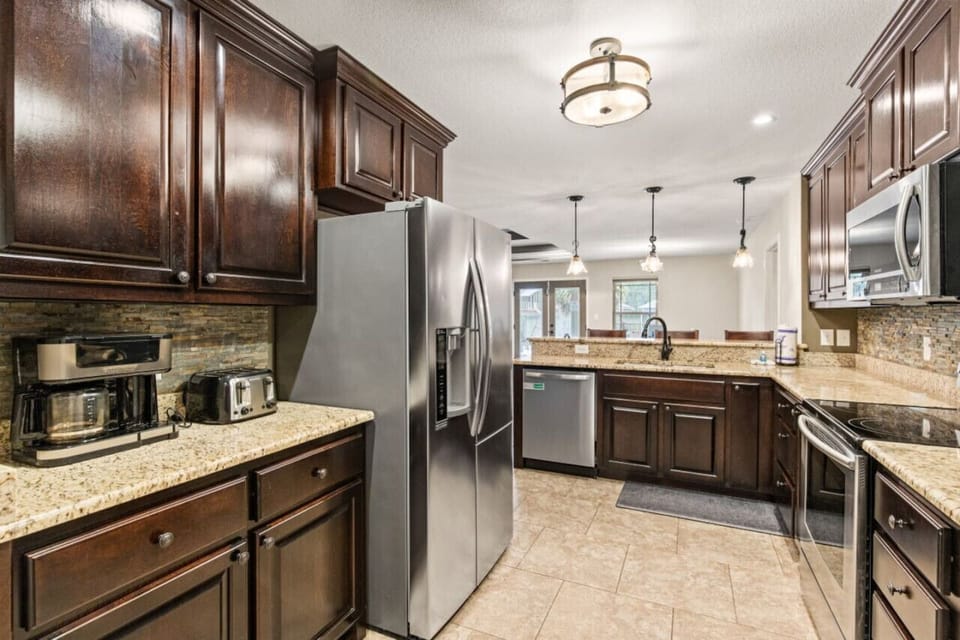 Relish in the warmth of a beautifully appointed kitchen, featuring all the essentials: refrigerator, dishwasher, wine fridge, electric range and stove, Keurig coffee maker, and bar top seating for three.