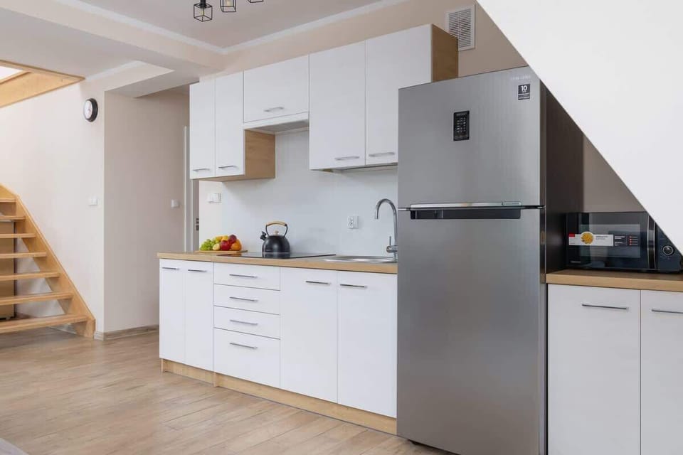 A fully equipped kitchenette in a modern design, including a large fridge and ample storage.

