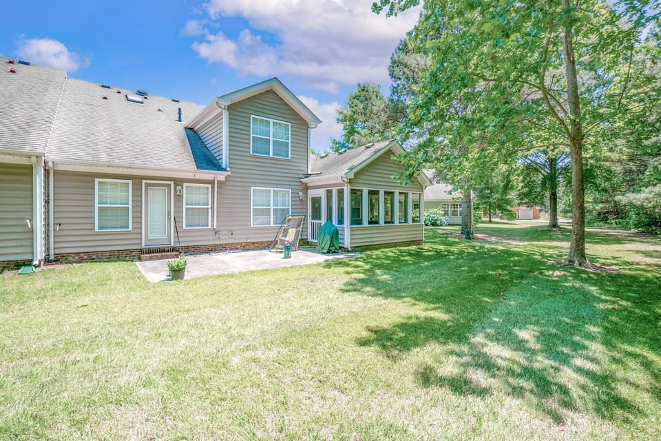 Tree-lined backyard with open lawn, patio, and screened-in porch.
