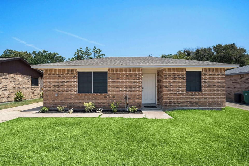 Charming Exterior: Bright brick home with lush lawn, perfect for sunny Seabrook adventures!