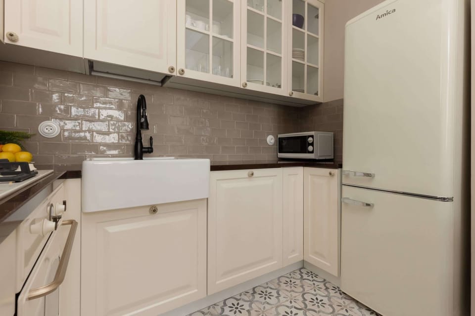 A close-up of the kitchen featuring white cabinets, a farmhouse sink, and modern appliances.

