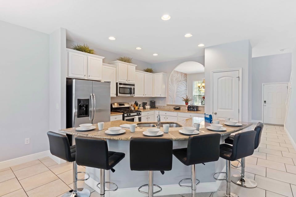 Lush kitchen of the home in Davenport Florida - Open-concept kitchen, fully furnished with stylish details - Breakfast bar with high chairs - Elegant and coordinated color palette for a cohesive look