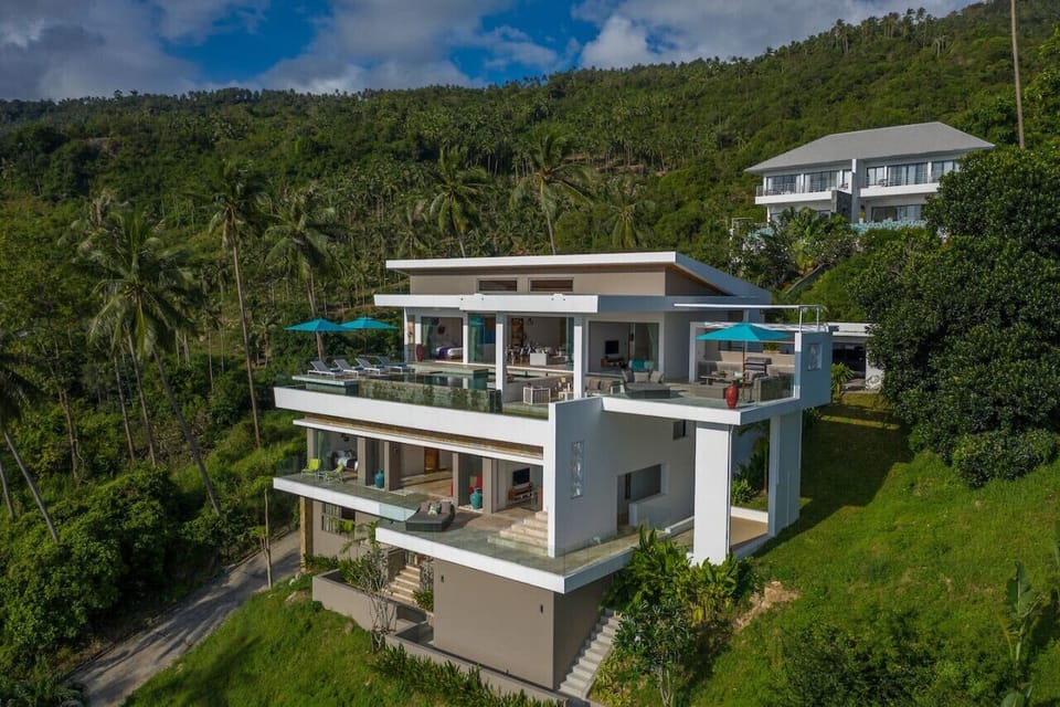 `Drone footage captures the villa`s majestic exterior, surrounded by lush tropical greenery and stunning mountain views.`
