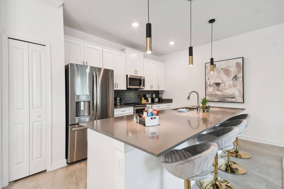 Welcome to a modern kitchen that combines style and function, featuring stainless steel appliances, stylish pendant lighting over a spacious island, and inviting quartz countertops perfect for casual dining with elegant barstools.