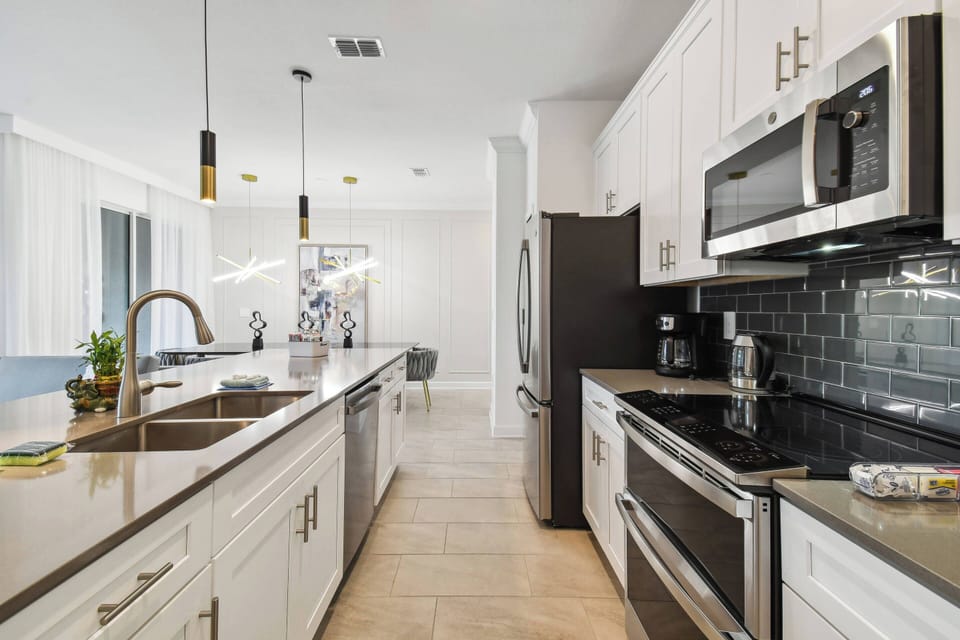 Experience a stunning modern kitchen with elegant white cabinetry, dark granite countertops, stainless steel appliances, and stylish pendant lighting—perfect for your culinary adventures and creating memorable meals.