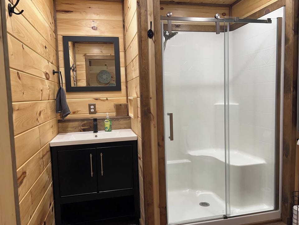 Shower with wand shower handle and a bench.