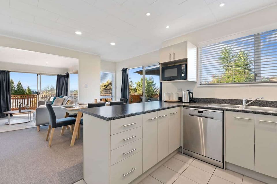 Fully-equipped modern kitchen with stone benchtops, stainless appliances and outdoor views — Rotorua self-contained rental