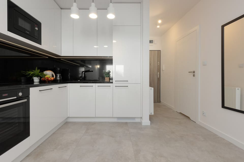 A modern kitchen with white cabinetry, black countertops, and integrated appliances.


