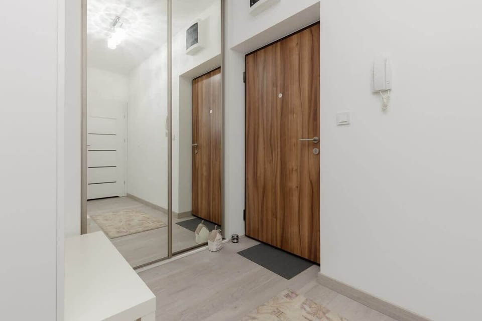 A hallway with wooden accents and clean white walls, creating a welcoming entrance.

