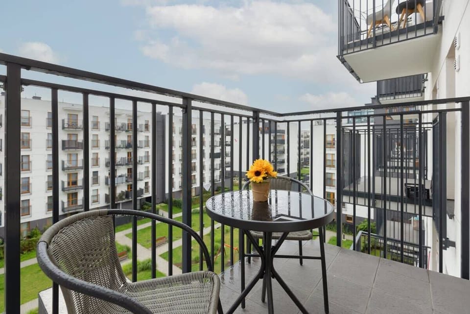 A balcony with a seating area, offering views of the modern residential complex.

