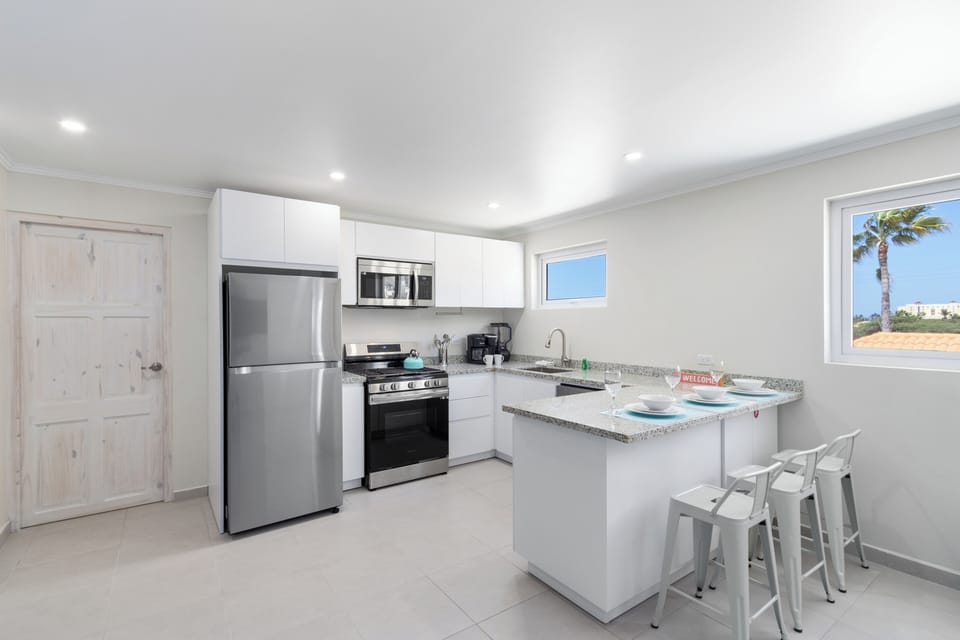 Fabulous and fully equipped Kitchen of the 2-BR Condo in Noord, Aruba - Availability of all kitchen accessories - Ample amount of storage - Beautiful lighting scheme - 3 stunning high chairs available - Beautiful views from the window of the Kitchen