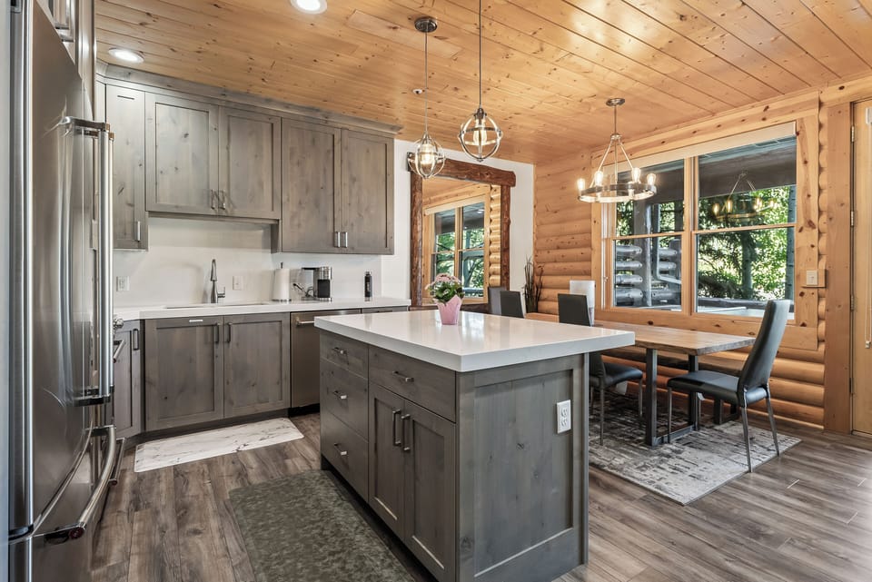 - Modern kitchen with stainless steel appliances and island  
- Spacious dining area with rustic wood accents and large windows  
- Perfect spot to gather and enjoy meals in a mountain cabin