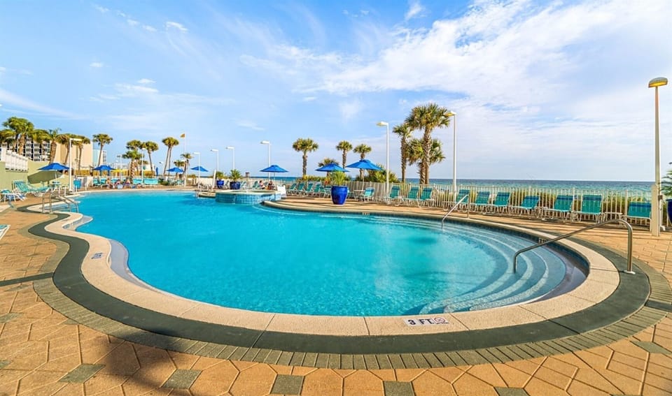 Sparkling beachfront pool with panoramic ocean views and palm trees creates your perfect tropical escape.