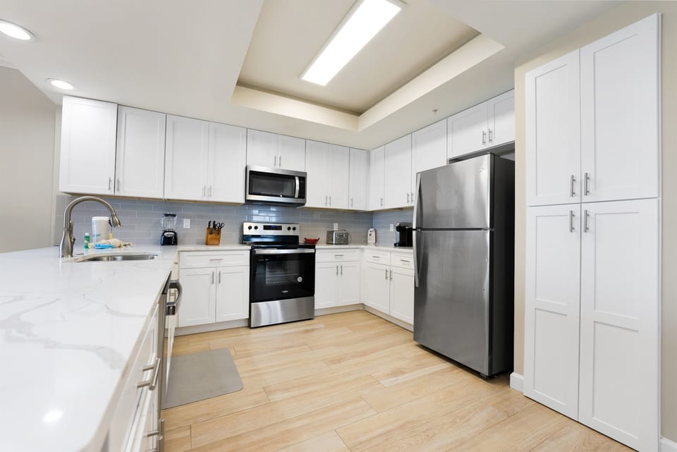 Your spacious kitchen features modern white cabinetry, stainless steel appliances, and everything you need to create memorable meals during your stay.