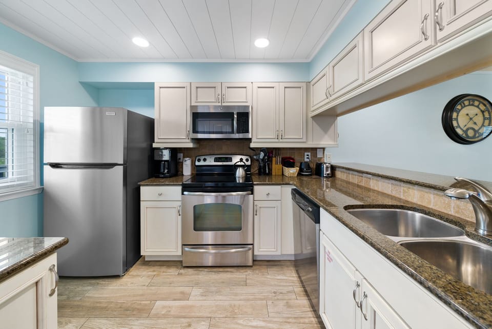 Your fully equipped kitchen features stainless steel appliances, granite counters, and coastal blue accents for memorable meal prep.