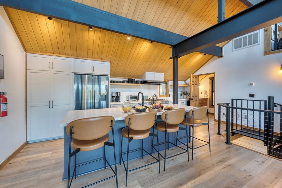Fully-equipped kitchen with modern appliances and barstool seating at the island counter.