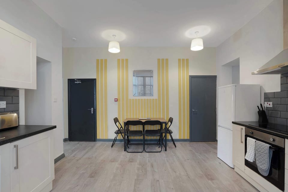 Gather around the dining table in this bright, open space, with comfortable seating and bold yellow accents. The spacious layout creates a welcoming setting for shared meals, relaxed conversations and easy moments together.