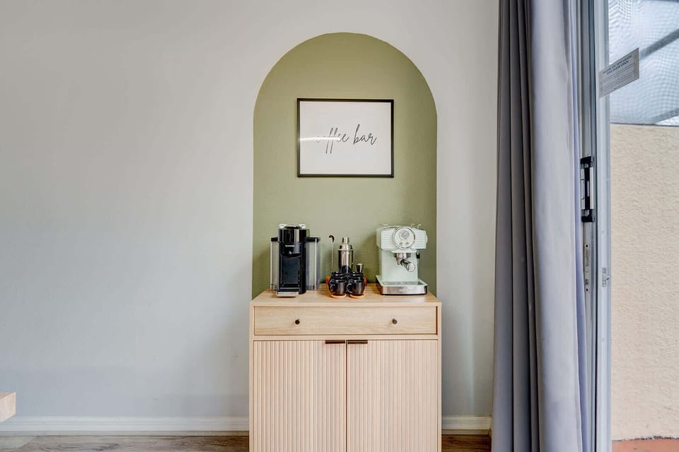 coffee bar with modern espresso machines set against a green accent wall