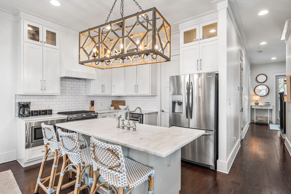 Bright kitchen with marble island seating, stainless steel appliances, and coastal-inspired style.