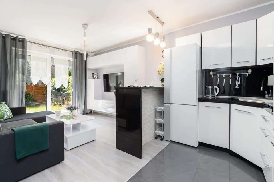 A modern, well-equipped kitchen with white cabinetry, a black countertop, and a cozy dining area.

