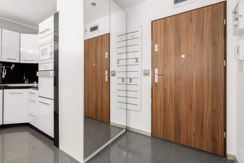 An entrance hallway with wooden doors, mirrored storage, and a clean, minimalist design.

