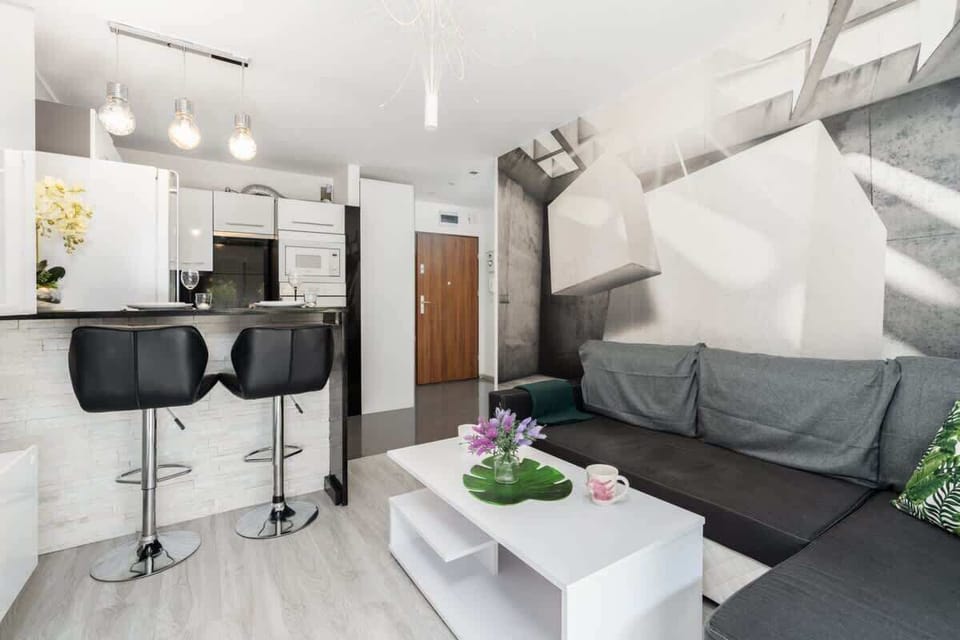 A spacious open-plan living area with a dining space featuring bar stools, modern furniture, and plenty of natural light.

