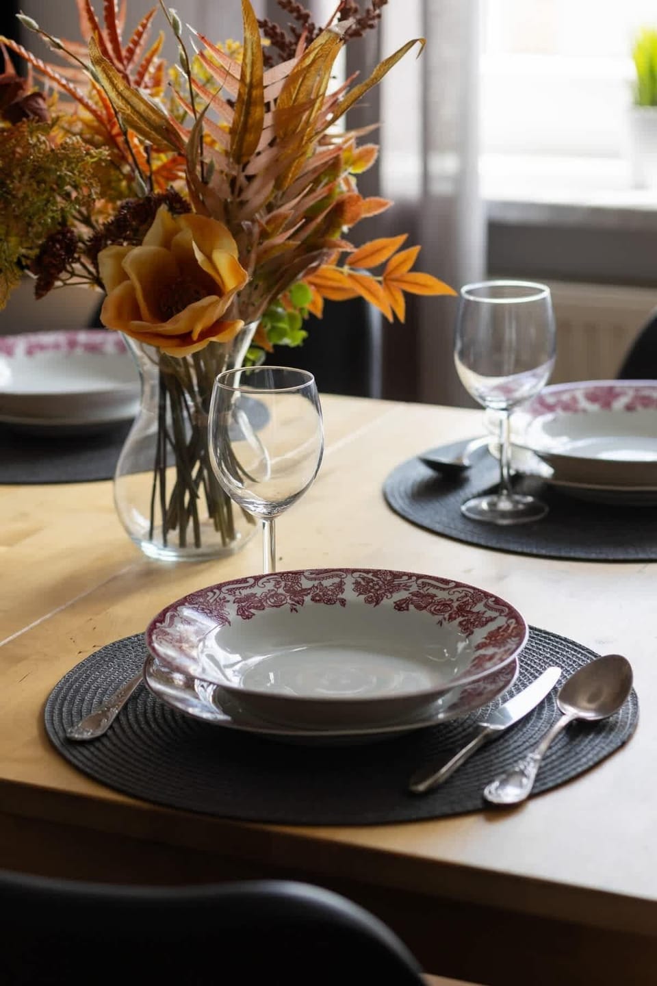 A stylish table setting with a vase of dried flowers, adding a warm decorative touch.

