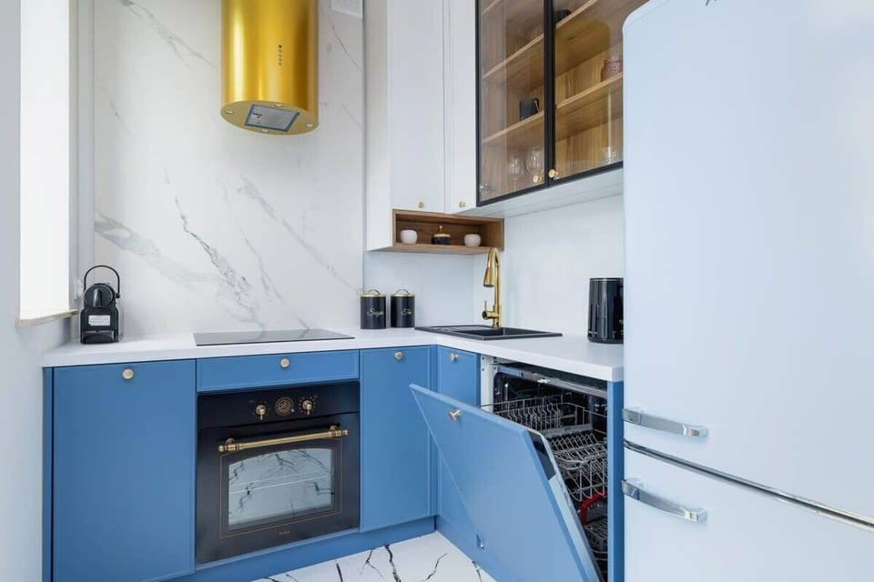 A modern kitchen with blue cabinets, gold accents, and marble details, combining luxury and functionality.

