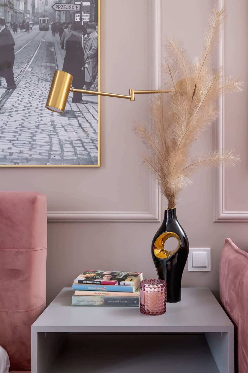 A decorative black vase with pampas grass and gold elements placed on a sleek side table.

