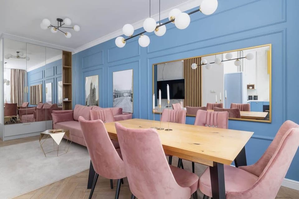 A spacious open-plan dining and living area with a stylish blue and pink color palette and elegant furnishings.

