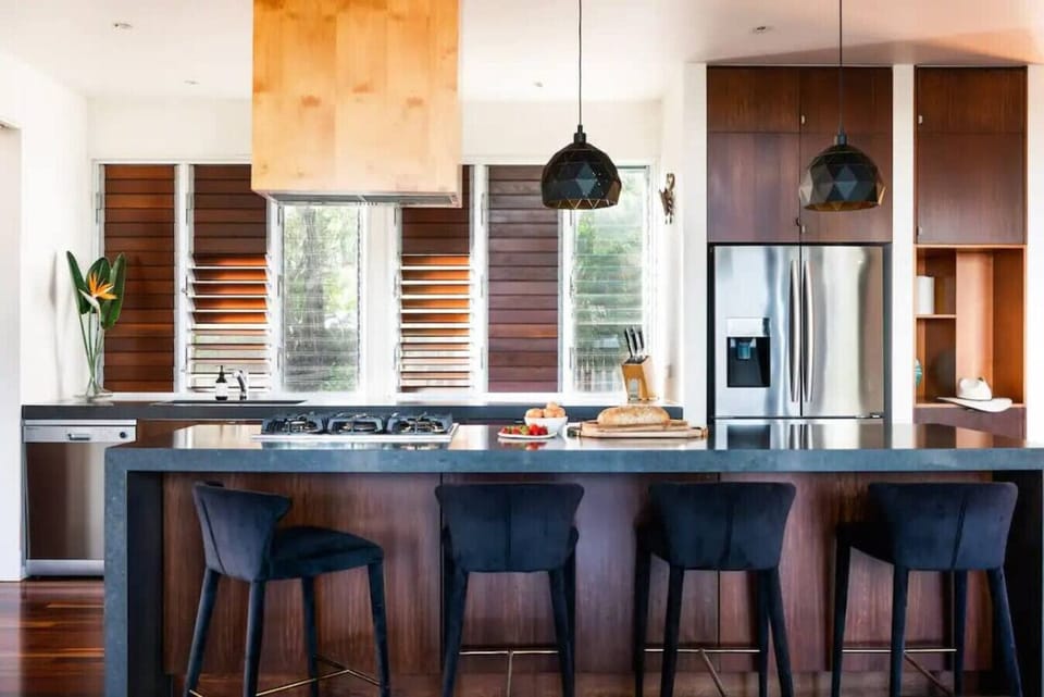 Kitchen with gas cooktop, electric oven, and simple pantry including tea, coffee, pods, oils, balsamic, spices, and provisions.