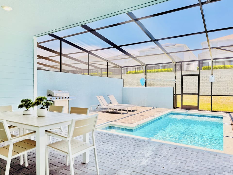 Screened pool deck with patio dining table, BBQ grill, and loungers.