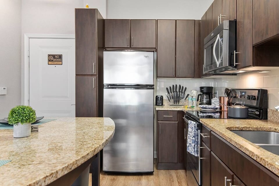 Full size fridge with ice maker, microwave, coffee maker, range, and oven - all for your at-home drink and meal needs.