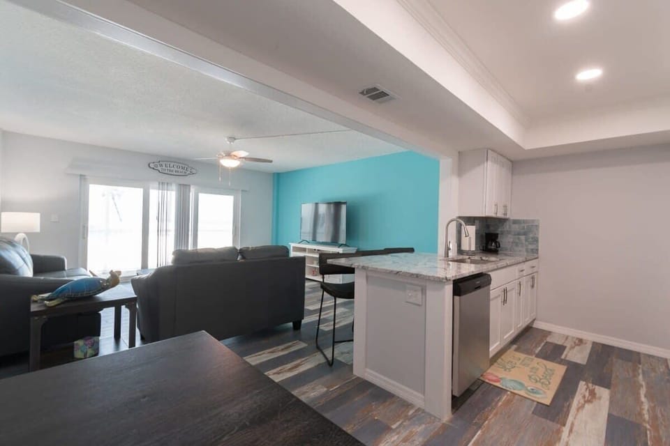 Open-concept living area with a coastal blue accent wall and modern kitchen island.