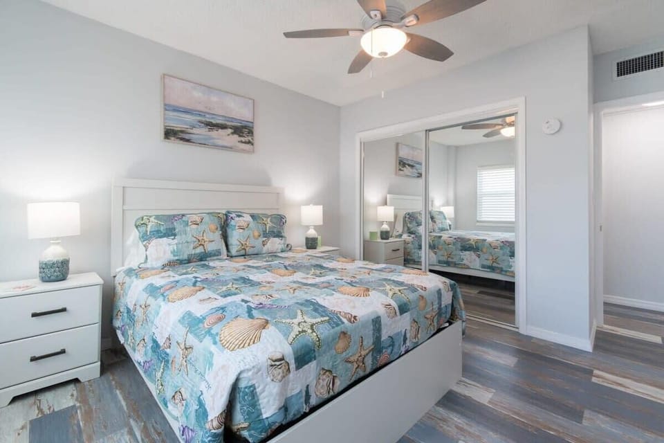 Coastal-themed bedroom with a queen bed and mirrored closet doors.