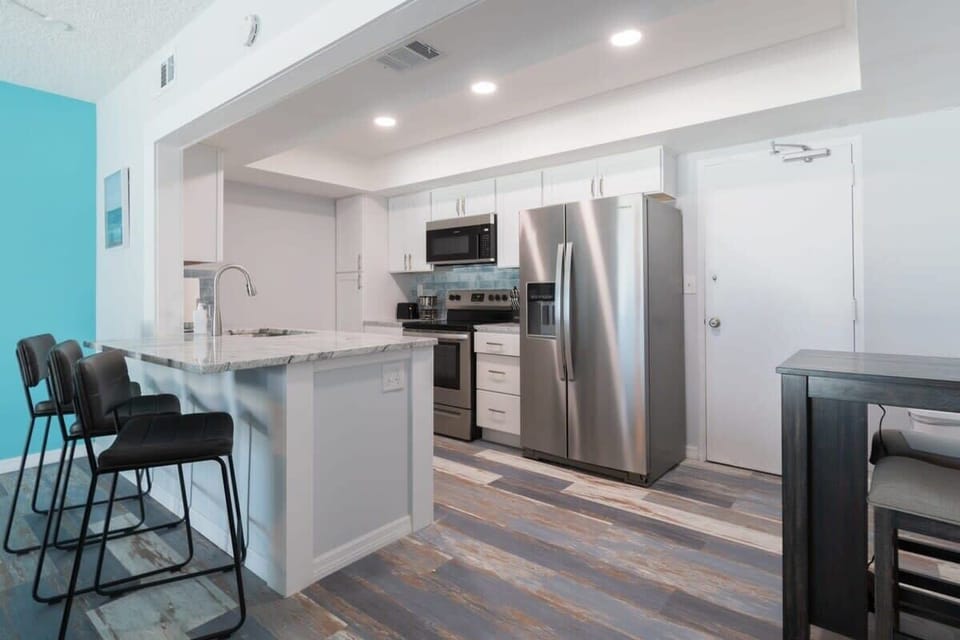 Modern kitchen with stainless steel appliances and a marble countertop island.