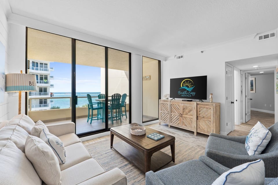 Relax in the open-concept living room with easy access to dining and a balcony overlooking the pool and Gulf.

Professionally Managed by
Breathe Easy Rentals