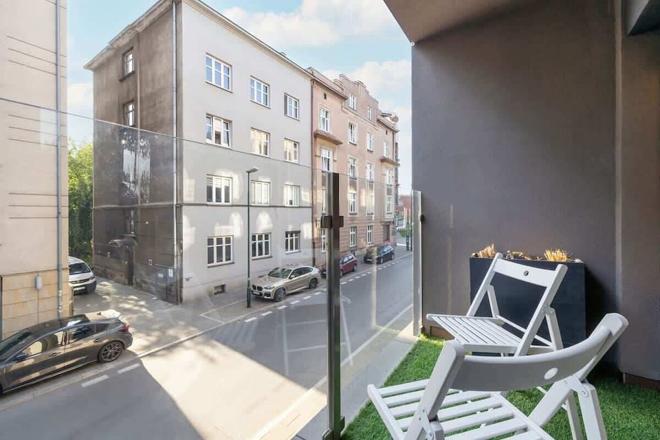 A balcony with outdoor seating, featuring chairs and a small table, perfect for enjoying a sunny day.

