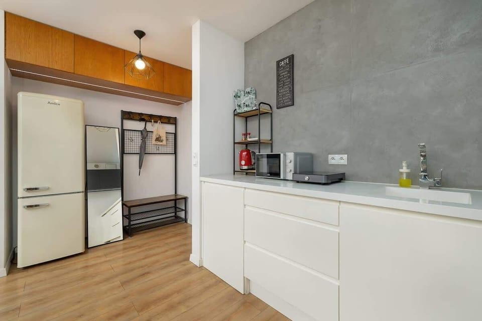 A modern kitchen with white cabinetry, a wooden countertop, and gray walls, equipped with all essentials.

