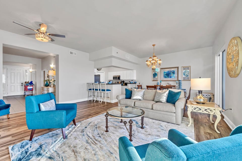 Relax in your stylish living space with vibrant teal accents, cozy seating, and an open layout connecting to your fully-equipped kitchen.