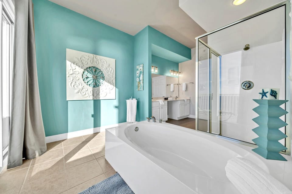 Soak your stress away in this spa-like bathroom featuring a luxurious deep soaking tub, elegant aqua walls, and bright natural light.