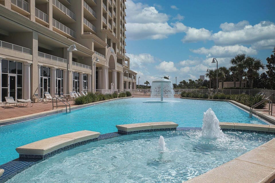 Elegant pool area with sparkling fountains and comfortable lounging spaces at this beachfront high-rise property.