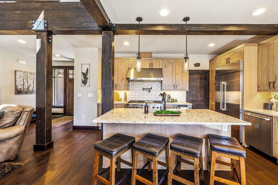 The expansive kitchen island features a spacious natural stone countertop, providing ample space for meal preparation and entertaining