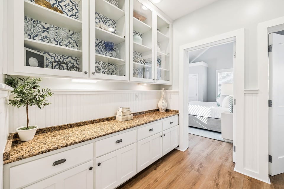 Your butler's pantry features elegant storage with beautiful patterned backing and granite counters for all your serving needs.