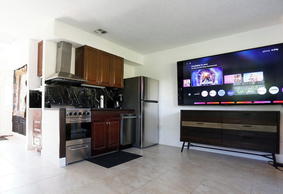 Kitchenette and view of living room with extra large TV on wall