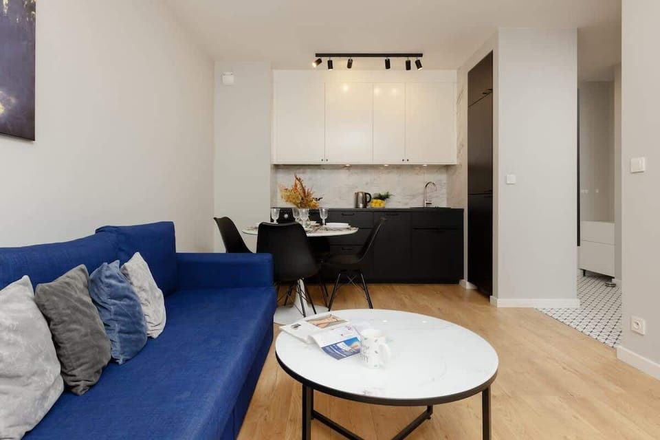 An open-concept living room connected to the kitchen, emphasizing a spacious layout and sleek furnishings.

