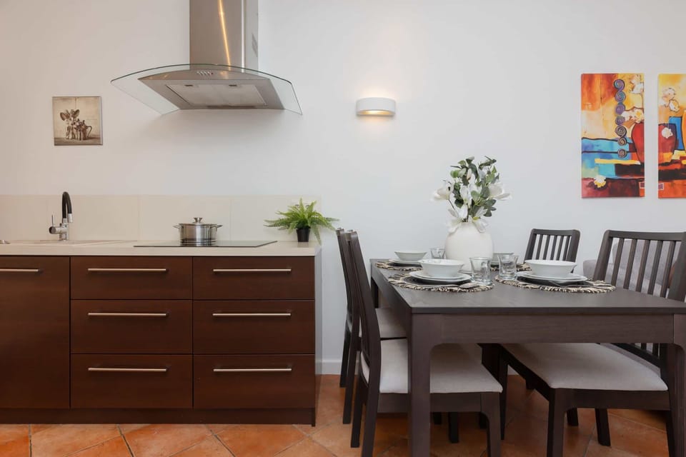A dining area adjacent to a modern kitchen, featuring wooden furniture and decorative touches.

