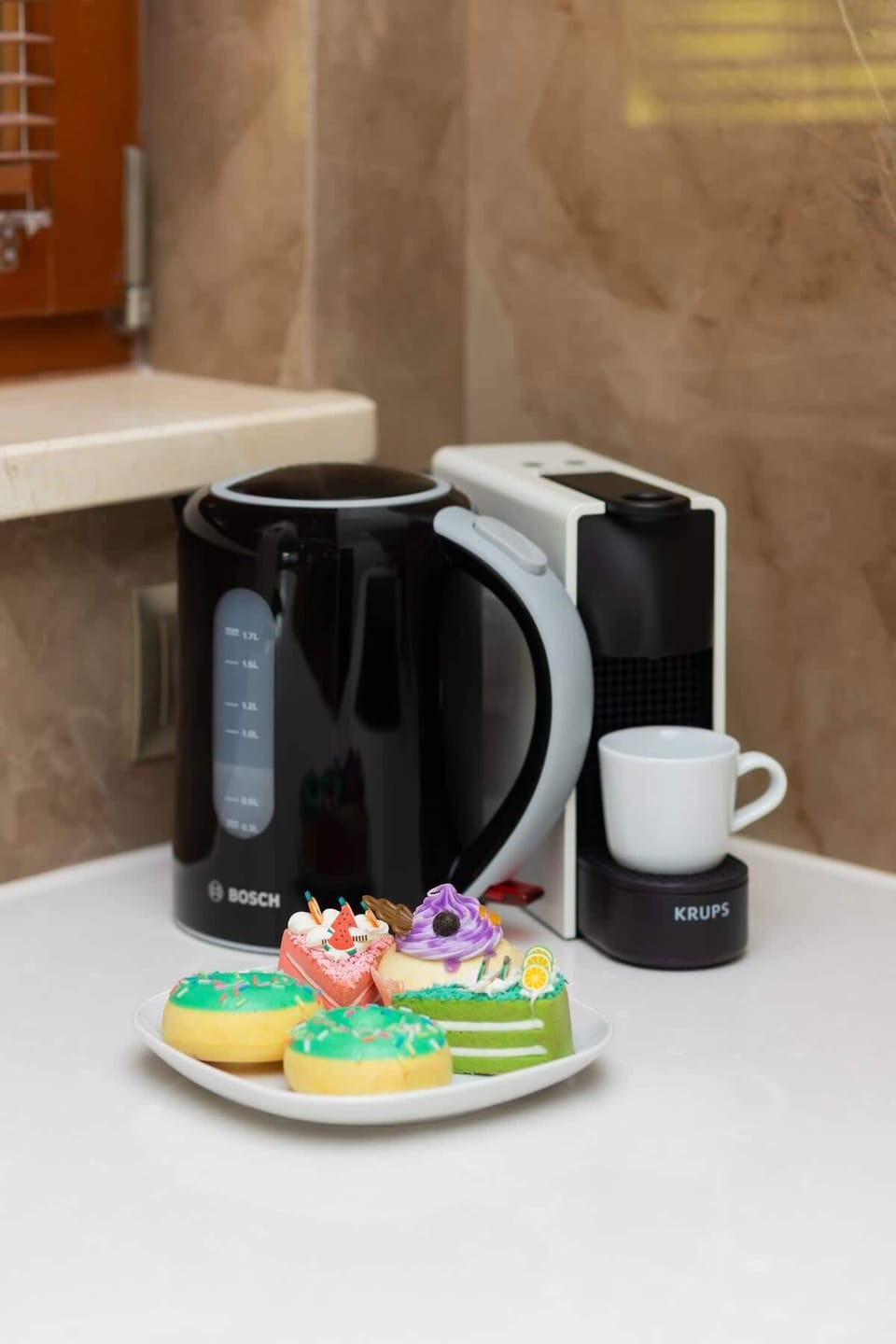 A closer look at the kitchen counter, featuring a coffee maker, colorful candies, and mugs for guest convenience.


